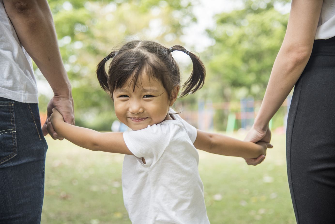young girl holding hands with her parent