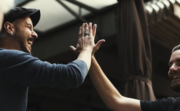 Two men holding their hands up together giving a high five