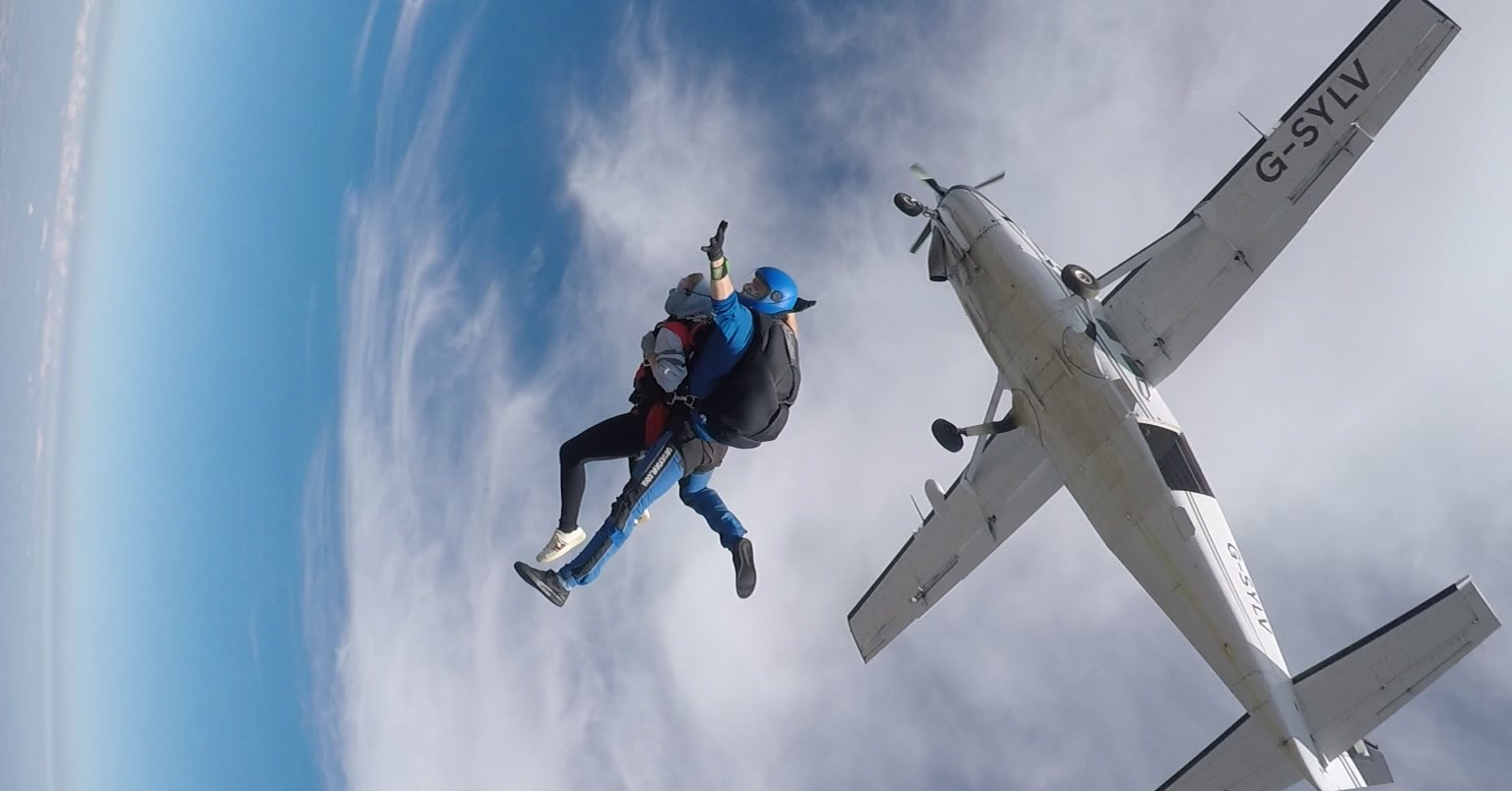 Two people skydiving strapped together falling from a plane