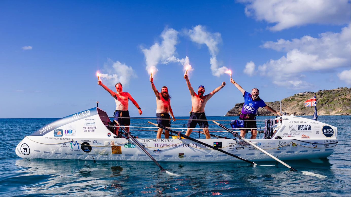 Four Veterans celebrating on a rowing boat after completing a long distance sea-crossing fundraiser.