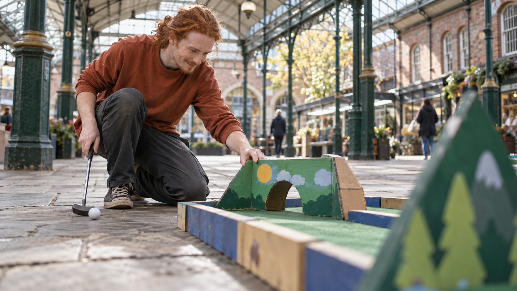 A fundraiser tests a homemade mini golf obstacle in a covered market courtyard.